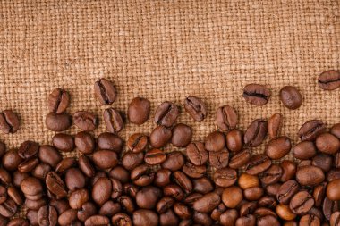 kahve çekirdekleri çuval bezi arka plan üzerinde. kavrulmuş kahvenin beyaz arka planda izole. Kavrulmuş kahve çekirdekleri arka plan kapatın. Kahve çekirdekleri kazık kopya alanı metin için beyaz zemin üzerine üstten