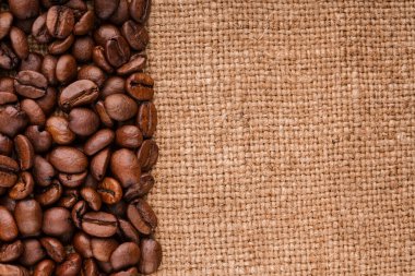kahve çekirdekleri çuval bezi arka plan üzerinde. kavrulmuş kahvenin beyaz arka planda izole. Kavrulmuş kahve çekirdekleri arka plan kapatın. Kahve çekirdekleri kazık kopya alanı metin için beyaz zemin üzerine üstten