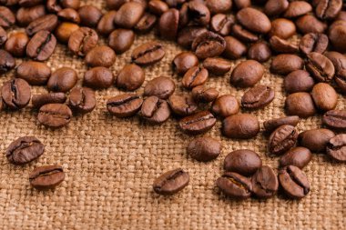 kahve çekirdekleri çuval bezi arka plan üzerinde. kavrulmuş kahvenin beyaz arka planda izole. Kavrulmuş kahve çekirdekleri arka plan kapatın. Kahve çekirdekleri kazık kopya alanı metin için beyaz zemin üzerine üstten