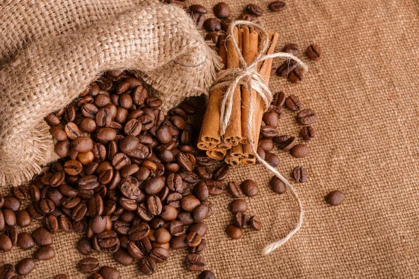 Kahve çekirdekleri ve tarçın çuval bezi bir arka plan üzerinde. Kavrulmuş kahve çekirdekleri arka plan kapatın. Üst metin kopyalama yeri olan kahve çekirdekleri kazık. Baharat. Baharat. Tarçın. Badian. Kahve evi.