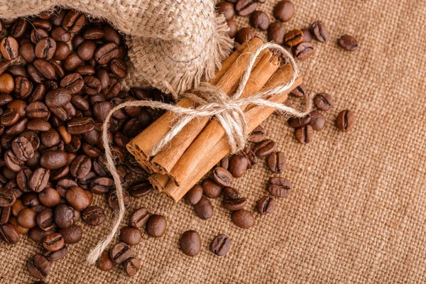 Kahve çekirdekleri ve tarçın çuval bezi bir arka plan üzerinde. Kavrulmuş kahve çekirdekleri arka plan kapatın. Üst metin kopyalama yeri olan kahve çekirdekleri kazık. Baharat. Baharat. Tarçın. Badian. Kahve evi.