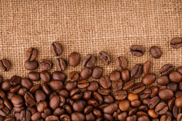 kahve çekirdekleri çuval bezi arka plan üzerinde. kavrulmuş kahvenin beyaz arka planda izole. Kavrulmuş kahve çekirdekleri arka plan kapatın. Kahve çekirdekleri kazık kopya alanı metin için beyaz zemin üzerine üstten