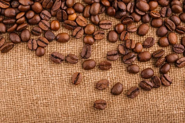 kahve çekirdekleri çuval bezi arka plan üzerinde. kavrulmuş kahvenin beyaz arka planda izole. Kavrulmuş kahve çekirdekleri arka plan kapatın. Kahve çekirdekleri kazık kopya alanı metin için beyaz zemin üzerine üstten