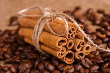 Kahve çekirdekleri ve tarçın çuval bezi bir arka plan üzerinde. Kavrulmuş kahve çekirdekleri arka plan kapatın. Üst metin kopyalama yeri olan kahve çekirdekleri kazık. Baharat. Baharat. Tarçın. Badian. Kahve evi.