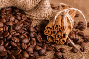 Kahve çekirdekleri ve tarçın çuval bezi bir arka plan üzerinde. Kavrulmuş kahve çekirdekleri arka plan kapatın. Üst metin kopyalama yeri olan kahve çekirdekleri kazık. Baharat. Baharat. Tarçın. Badian. Kahve evi.