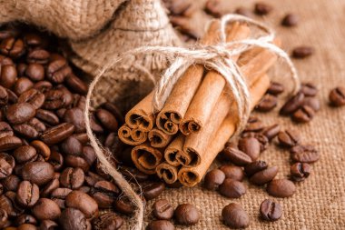 Kahve çekirdekleri ve tarçın çuval bezi bir arka plan üzerinde. Kavrulmuş kahve çekirdekleri arka plan kapatın. Üst metin kopyalama yeri olan kahve çekirdekleri kazık. Baharat. Baharat. Tarçın. Badian. Kahve evi.