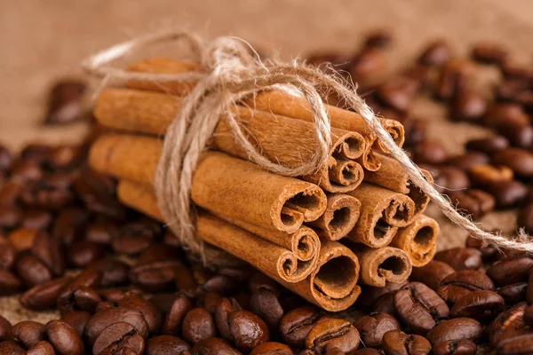 Kahve çekirdekleri ve tarçın çuval bezi bir arka plan üzerinde. Kavrulmuş kahve çekirdekleri arka plan kapatın. Üst metin kopyalama yeri olan kahve çekirdekleri kazık. Baharat. Baharat. Tarçın. Badian. Kahve evi.