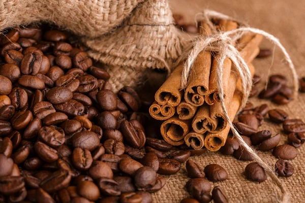 Kahve çekirdekleri ve tarçın çuval bezi bir arka plan üzerinde. Kavrulmuş kahve çekirdekleri arka plan kapatın. Üst metin kopyalama yeri olan kahve çekirdekleri kazık. Baharat. Baharat. Tarçın. Badian. Kahve evi.
