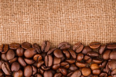 kahve çekirdekleri çuval bezi arka plan üzerinde. kavrulmuş kahvenin beyaz arka planda izole. Kavrulmuş kahve çekirdekleri arka plan kapatın. Kahve çekirdekleri kazık kopya alanı metin için beyaz zemin üzerine üstten