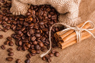 Kahve çekirdekleri ve tarçın çuval bezi bir arka plan üzerinde. Kavrulmuş kahve çekirdekleri arka plan kapatın. Üst metin kopyalama yeri olan kahve çekirdekleri kazık. Baharat. Baharat. Tarçın. Badian. Kahve evi.