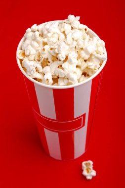 Kırmızı ve beyaz karton kutu içinde patlamış mısır. Patlamış mısır sınır üzerinde beyaz izole. Film. Fast food. Mısır