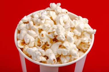 Kırmızı ve beyaz karton kutu içinde patlamış mısır. Patlamış mısır sınır üzerinde beyaz izole. Film. Fast food. Mısır