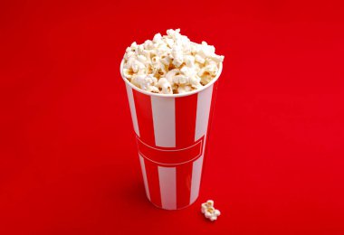 Kırmızı ve beyaz karton kutu içinde patlamış mısır. Patlamış mısır sınır üzerinde beyaz izole. Film. Fast food. Mısır