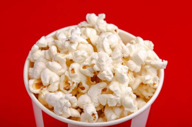 Kırmızı ve beyaz karton kutu içinde patlamış mısır. Patlamış mısır sınır üzerinde beyaz izole. Film. Fast food. Mısır