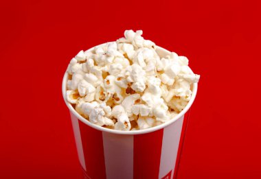 Kırmızı ve beyaz karton kutu içinde patlamış mısır. Patlamış mısır sınır üzerinde beyaz izole. Film. Fast food. Mısır