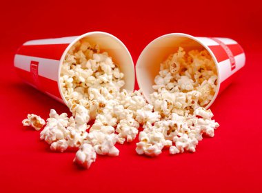 Kırmızı ve beyaz karton kutu içinde patlamış mısır. Patlamış mısır sınır üzerinde beyaz izole. Film. Fast food. Mısır