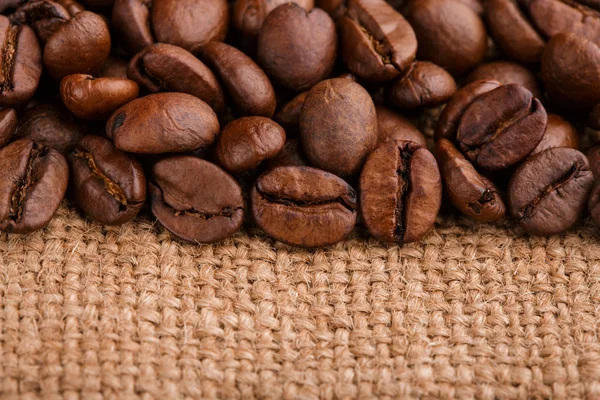kahve çekirdekleri çuval bezi arka plan üzerinde. kavrulmuş kahvenin beyaz arka planda izole. Kavrulmuş kahve çekirdekleri arka plan kapatın. Kahve çekirdekleri kazık kopya alanı metin için beyaz zemin üzerine üstten