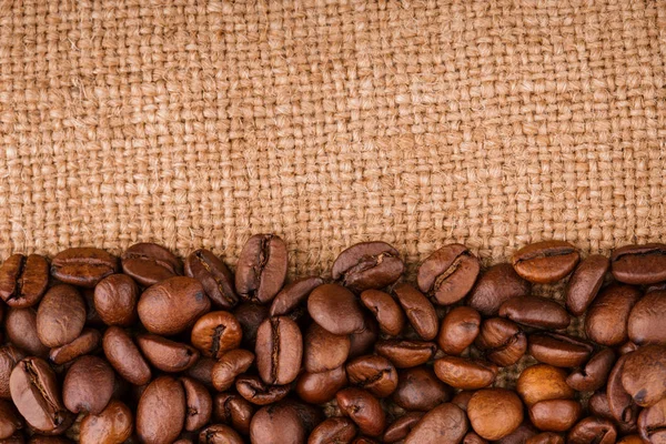 kahve çekirdekleri çuval bezi arka plan üzerinde. kavrulmuş kahvenin beyaz arka planda izole. Kavrulmuş kahve çekirdekleri arka plan kapatın. Kahve çekirdekleri kazık kopya alanı metin için beyaz zemin üzerine üstten