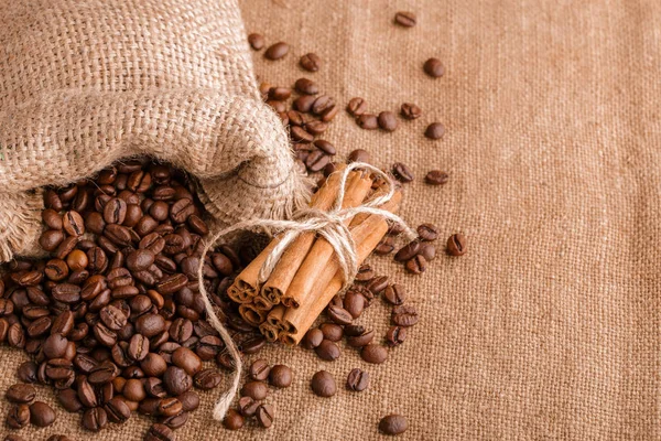 Kahve çekirdekleri ve tarçın çuval bezi bir arka plan üzerinde. Kavrulmuş kahve çekirdekleri arka plan kapatın. Üst metin kopyalama yeri olan kahve çekirdekleri kazık. Baharat. Baharat. Tarçın. Badian. Kahve evi.