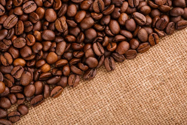 kahve çekirdekleri çuval bezi arka plan üzerinde. kavrulmuş kahvenin beyaz arka planda izole. Kavrulmuş kahve çekirdekleri arka plan kapatın. Kahve çekirdekleri kazık kopya alanı metin için beyaz zemin üzerine üstten