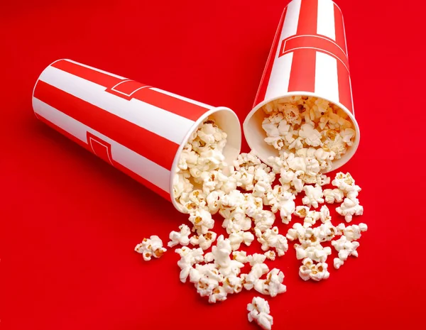 Kırmızı ve beyaz karton kutu içinde patlamış mısır. Patlamış mısır sınır üzerinde beyaz izole. Film. Fast food. Mısır