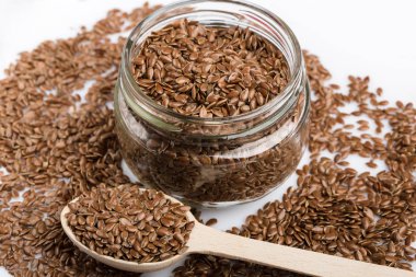 Beyaz arka plan üzerinde izole keten tohumu kapatın. Kase kahverengi keten tohumu ya da keten tohumu dolu. Tahıllar. Vitaminler. Sağlıklı gıda.