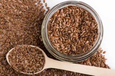 Beyaz arka plan üzerinde izole keten tohumu kapatın. Kase kahverengi keten tohumu ya da keten tohumu dolu. Tahıllar. Vitaminler. Sağlıklı gıda.