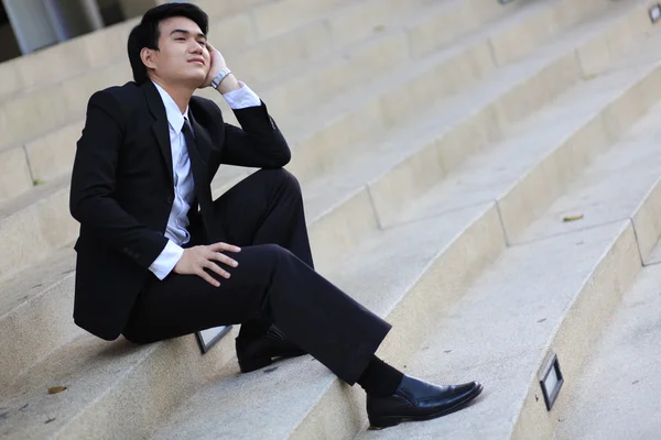 Retrato de un joven hombre de negocios guapo sonriente sentado en las escaleras —  Fotos de Stock