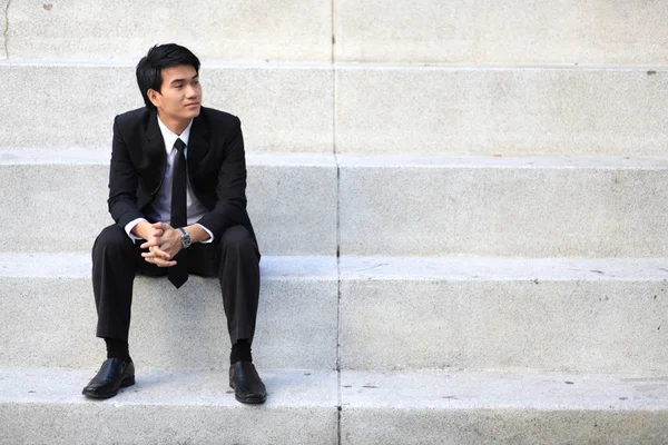 Retrato de un joven hombre de negocios guapo sonriente sentado en las escaleras —  Fotos de Stock
