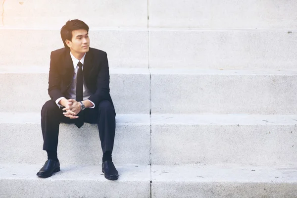 Retrato de joven hombre de negocios guapo sonriente sentado en las escaleras —  Fotos de Stock