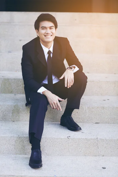 Retrato de joven hombre de negocios guapo sonriente sentado en las escaleras —  Fotos de Stock