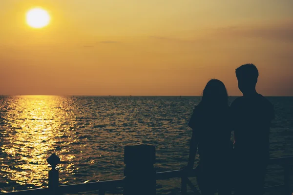 Silhuetas de casal abraçando contra o mar ao pôr do sol . — Fotografia de Stock