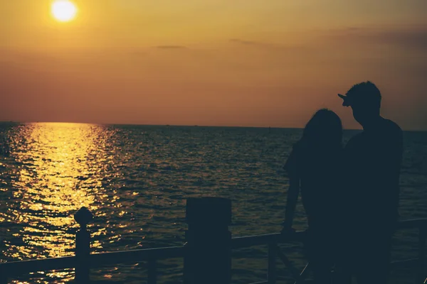 Sziluettek átölelve pár ellen a tengerre a naplemente. — Stock Fotó