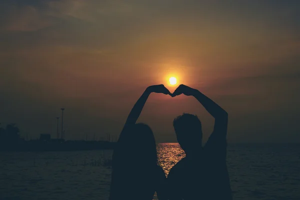 Silhouetten eines sich umarmenden Paares gegen das Meer bei Sonnenuntergang. — Stockfoto