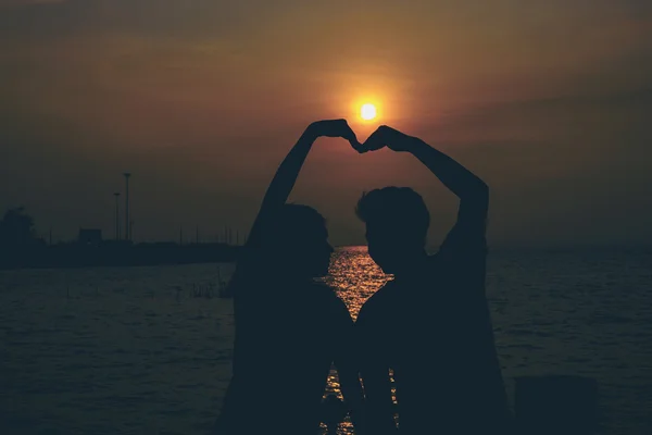 Silhouettes of hugging couple against the sea at sunset.