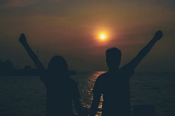 Silhouetten eines sich umarmenden Paares gegen das Meer bei Sonnenuntergang. — Stockfoto