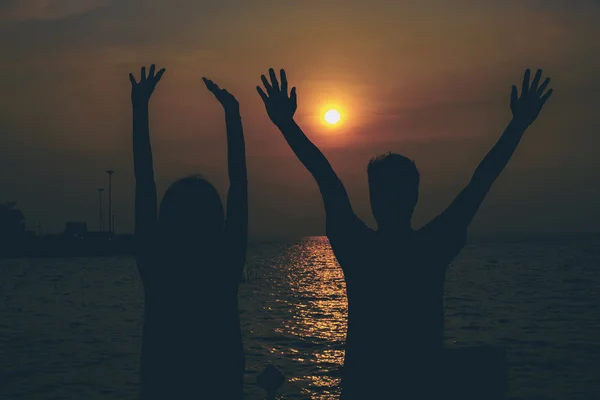 Silhouetten eines sich umarmenden Paares gegen das Meer bei Sonnenuntergang. — Stockfoto