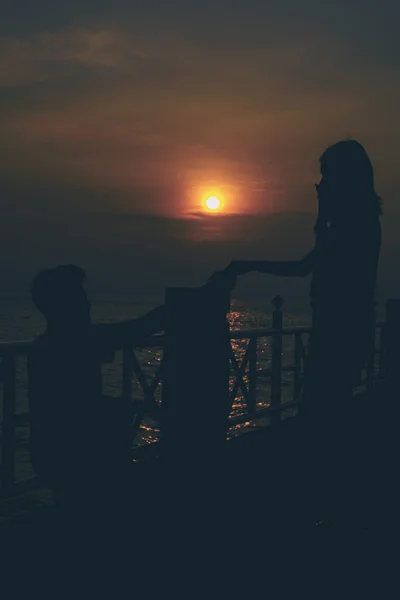 Silhouetten eines sich umarmenden Paares gegen das Meer bei Sonnenuntergang. — Stockfoto