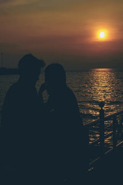 Silhuetas de casal abraçando contra o mar ao pôr do sol . — Fotografia de Stock