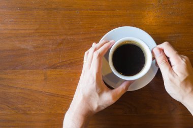 Üstten Görünüm el adamın bir fincan sıcak kahve eski ahşap masa üzerinde tutun