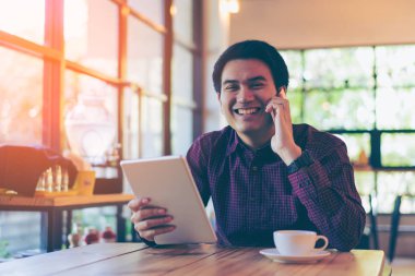 Genç Asyalı yakışıklı işadamı masasına okunurken gülümseyen