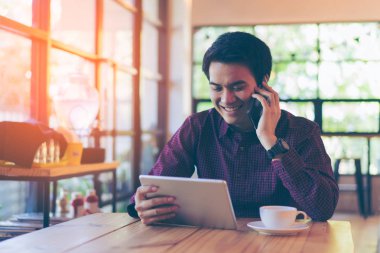 Genç Asyalı yakışıklı işadamı masasına okunurken gülümseyen