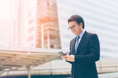 Genç Asyalı yakışıklı işadamı gülümseyen ile Smartphone kullanarak 