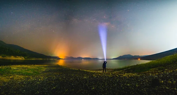 Silhouette uomo con torcia elettrica e Via Lattea galassia al lago — Foto Stock