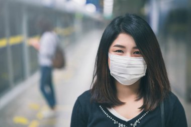 Metroda kirlenmiş hava ya da öğleden sonra 2.5 ve Coronavirus hastalığı ya da tüm dünyada COVID-19 salgını nedeniyle koruyucu yüz maskesi takan genç Asyalı bir kadın görülüyor..