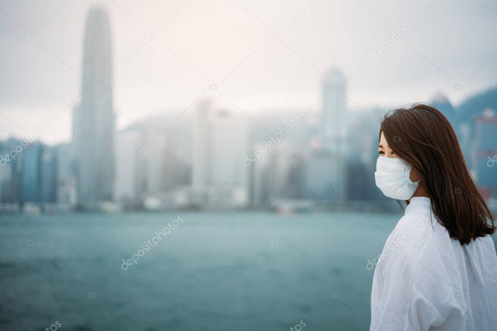 Young asian woman wearing protective face mask in city due to the polluted air or pm 2.5 and Coronavirus disease or COVID-19 outbreak situation in Hong Kong China and all of landmass in the world.