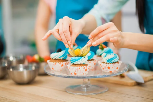 Крупный план женские руки украшения чашки торты — стоковое фото