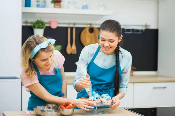 İki genç kız krem ile cupcakes dekorasyon