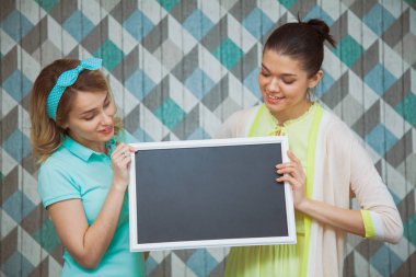 Elinde boş yazı tahtası ile iki çekici kadın.