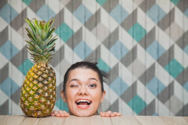 Beautiful girl's head and fresh pineapple on wooden table. — Stock Photo, Image